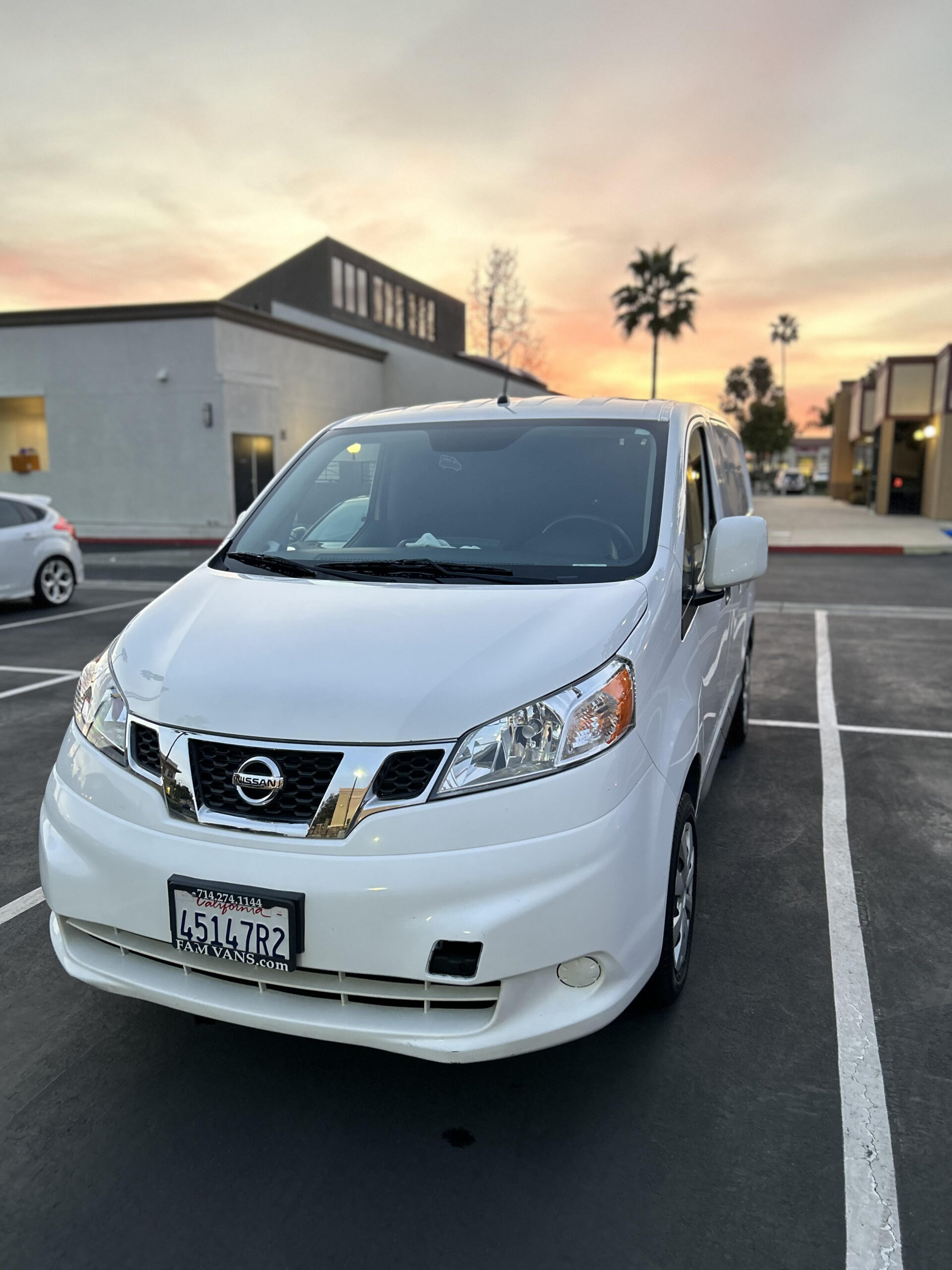 Clean White Nissan Van with beautiful sunset background and palm trees.